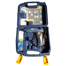 Charger l'image dans la galerie, L’image montre un pistolet à colle électrique posé sur une surface. Le pistolet à colle est bleu et jaune et comporte une petit embout noir à l’avant. Il est ranger dans une mallette de couleur bleu